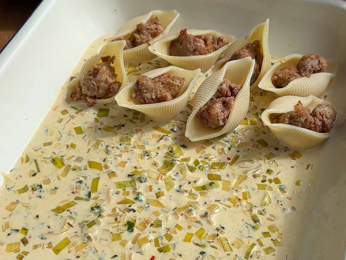 pasta shells being stuffed with sausage 
