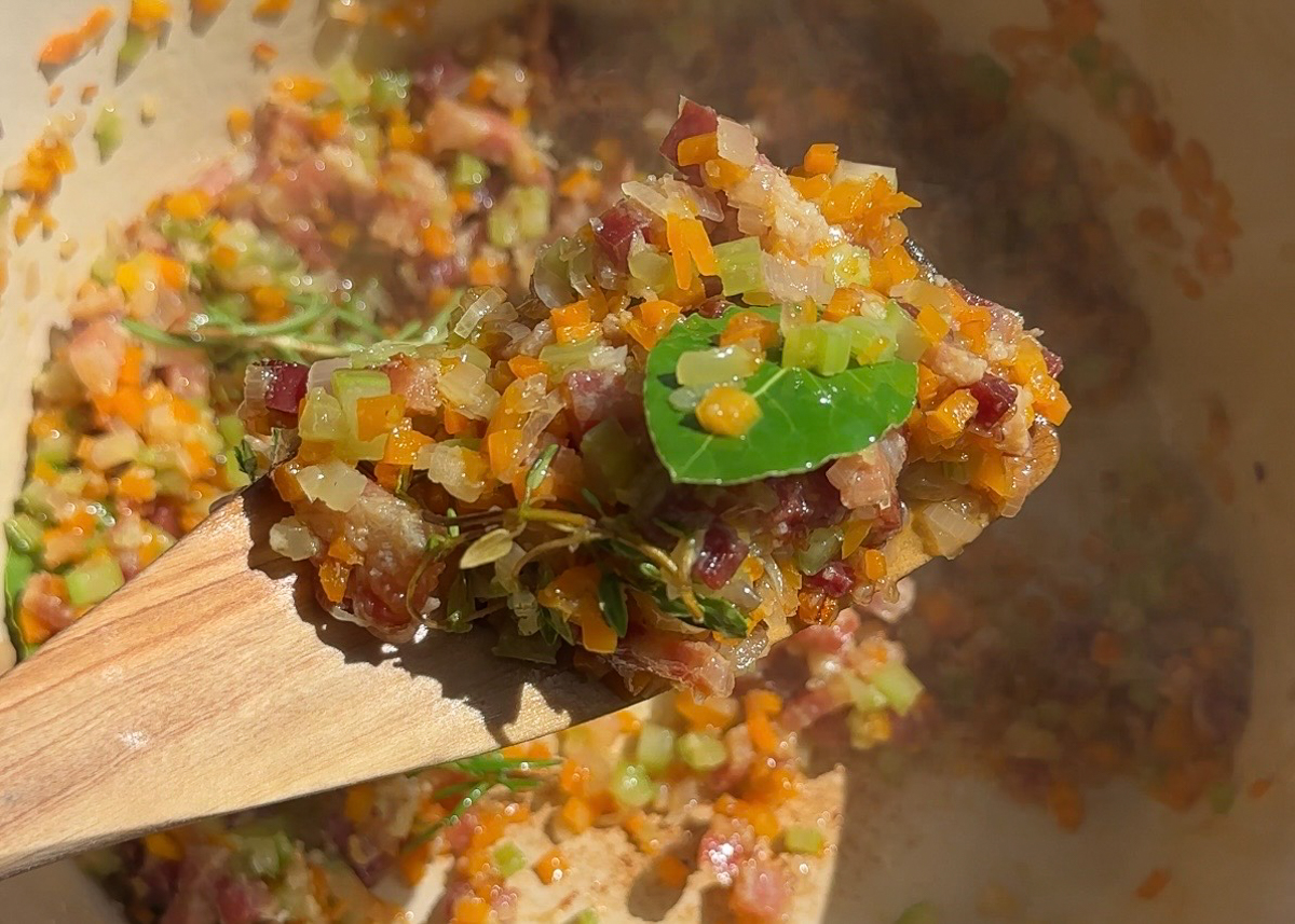 Classic soffritto of onion, carrot and celery sautéing in a pan for Italian bean soup.