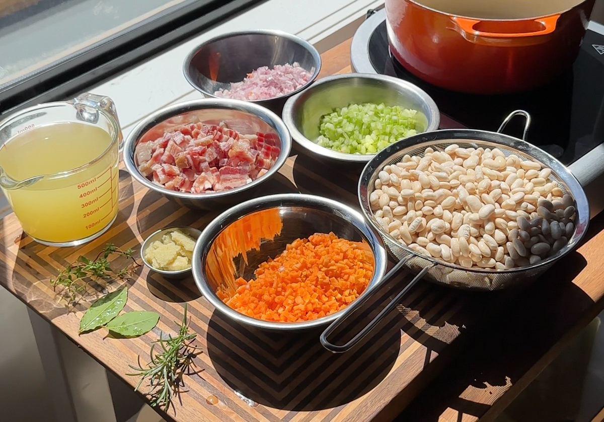 Ingredients for Tuscan white bean and pancetta soup including Great Northern beans, pancetta, carrot, celery, onion and fresh herbs