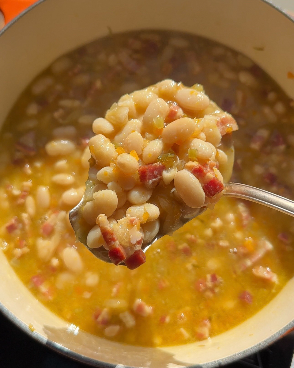 Creamy Tuscan white bean soup with crispy pancetta pieces and golden broth