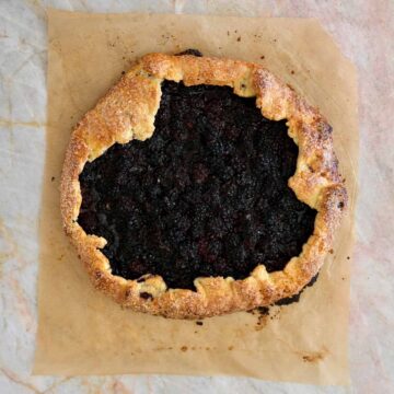 Freshly baked blackberry galette with golden flaky pastry and dark jammy blackberry filling.