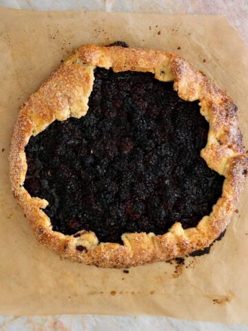 Freshly baked blackberry galette with golden flaky pastry and dark jammy blackberry filling.