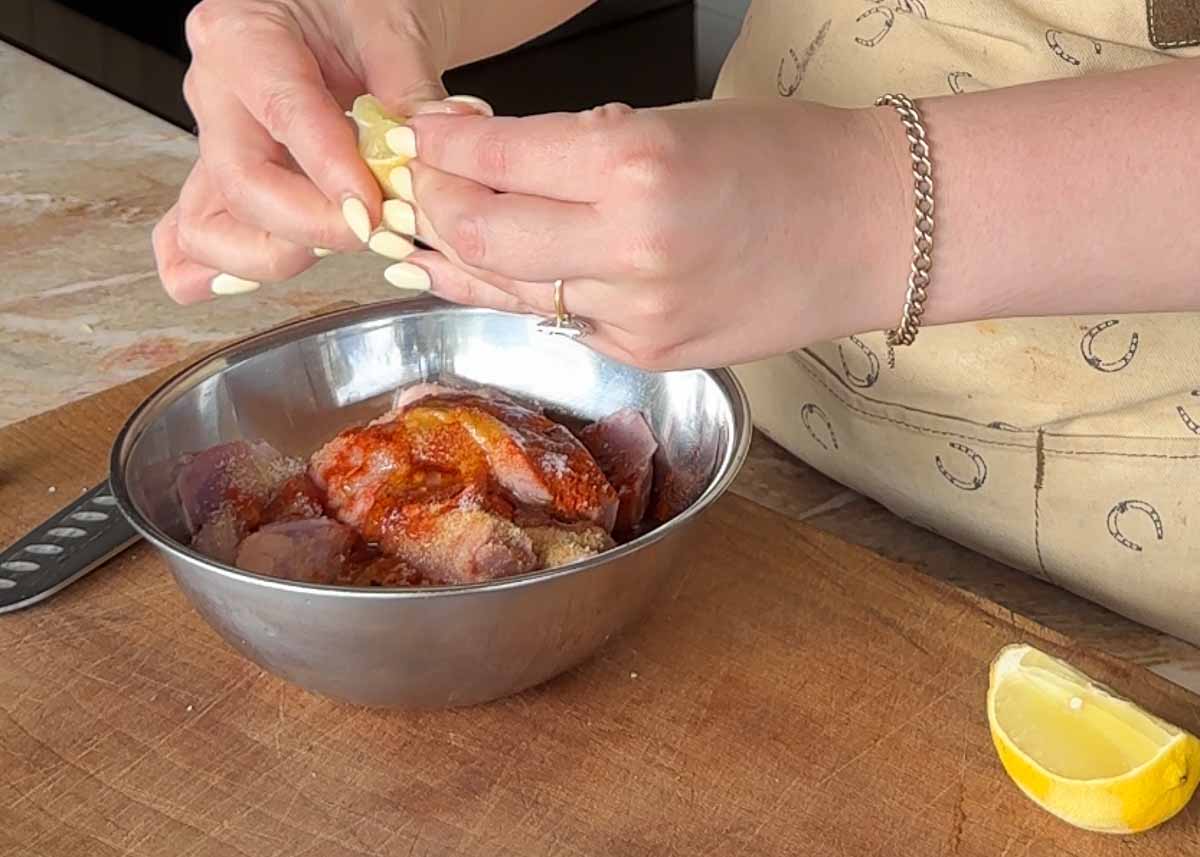 Adding lemon juice to marinated chicken thighs before grilling