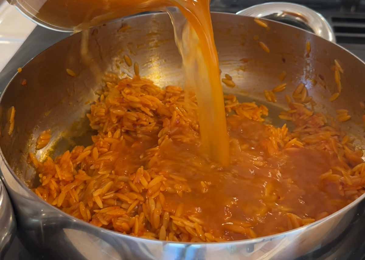 Prawn stock being added to orzo for saffron prawn orzo recipe