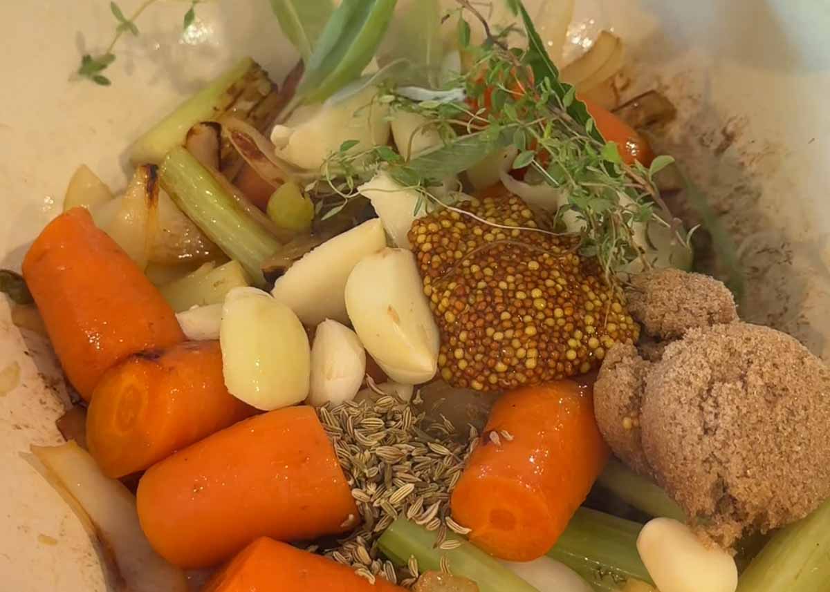 Vegetables, garlic and herbs simmering for a beer braised pork shoulder sauce