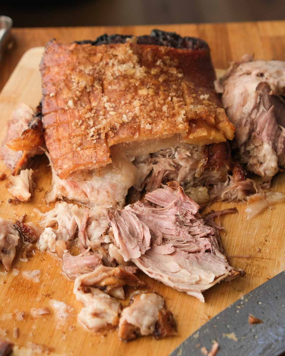 Slow cooked beer braised pork shoulder with crispy crackling and tender pulled meat on a board