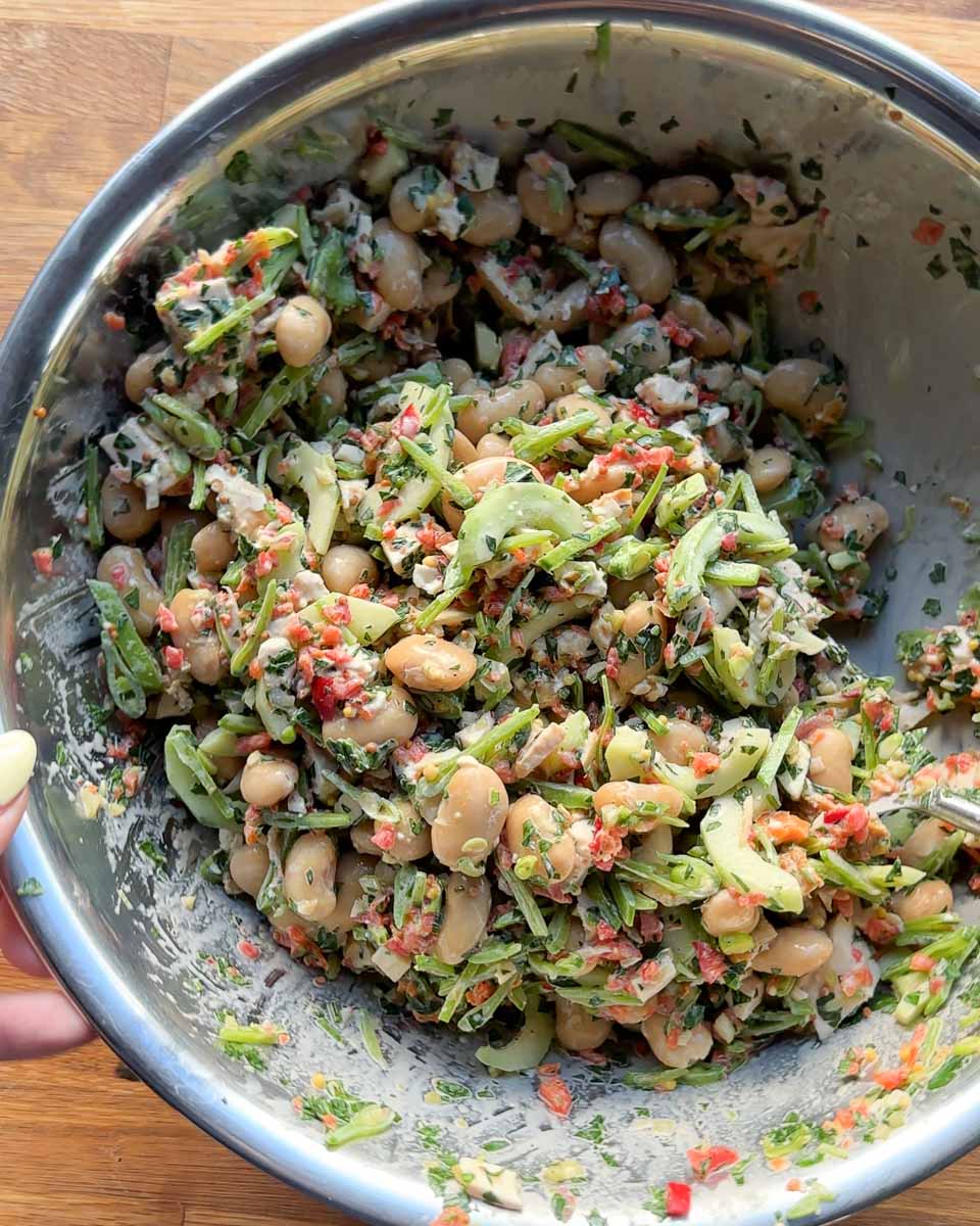 Close-up of rotisserie chicken butter bean salad tossed with cucumber, snow peas and herbs