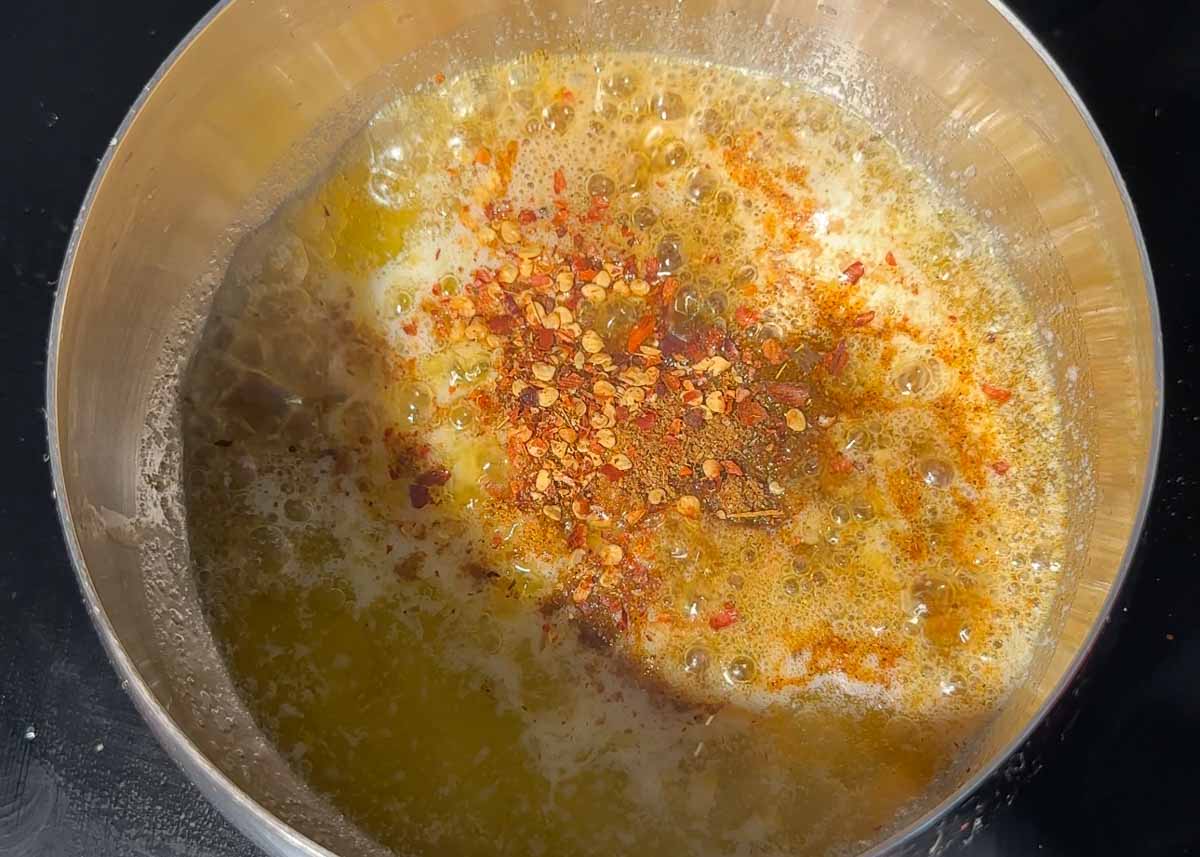 Butter melting with curry spices and chilli flakes to make curry butter