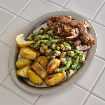 Grilled chicken with chimichurri butter bean salad and crispy potatoes served on a plate