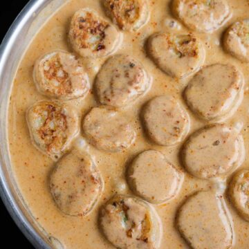 Close up of crispy prawn rice paper dumplings coated in creamy Thai red curry sauce