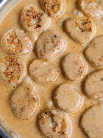 Close up of crispy prawn rice paper dumplings coated in creamy Thai red curry sauce