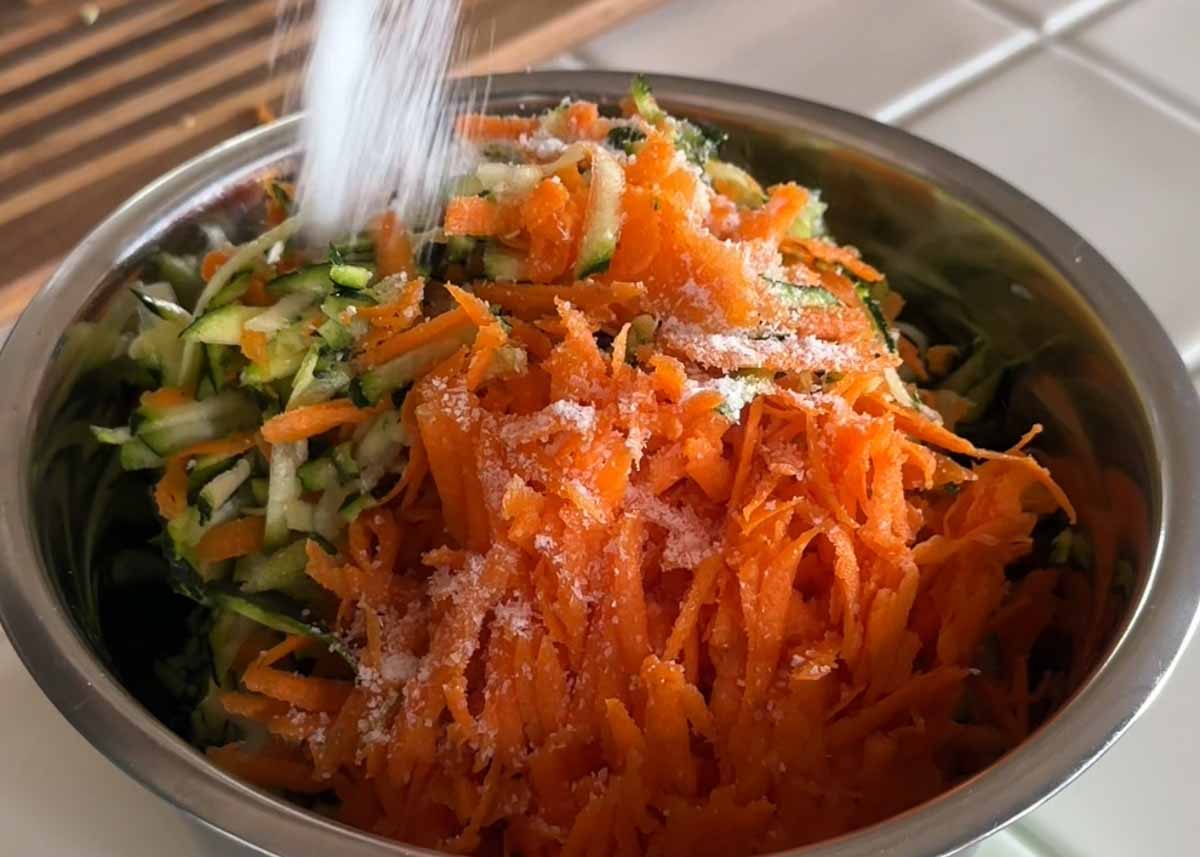 Grated zucchini and carrot being mixed for fritters