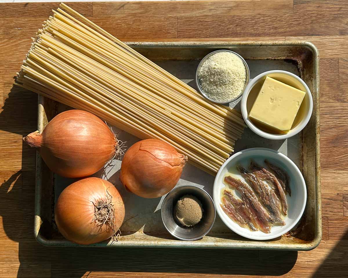 Ingredients for caramelised onion and anchovy spaghetti including onions, anchovies, garlic, butter and spaghetti