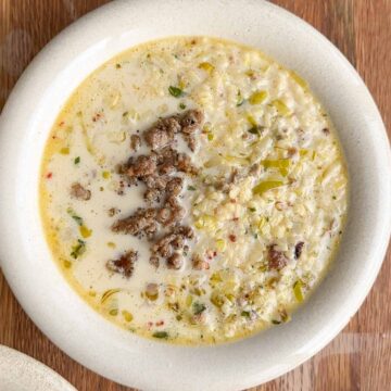creamy pork and fennel sausage pasta soup in a white bowl with alphabet pasta and crispy sausage
