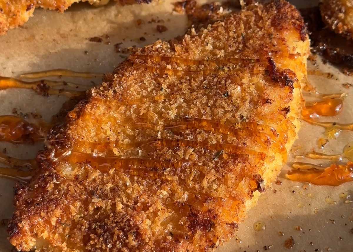 hot honey drizzling over baked parmesan crumbed chicken