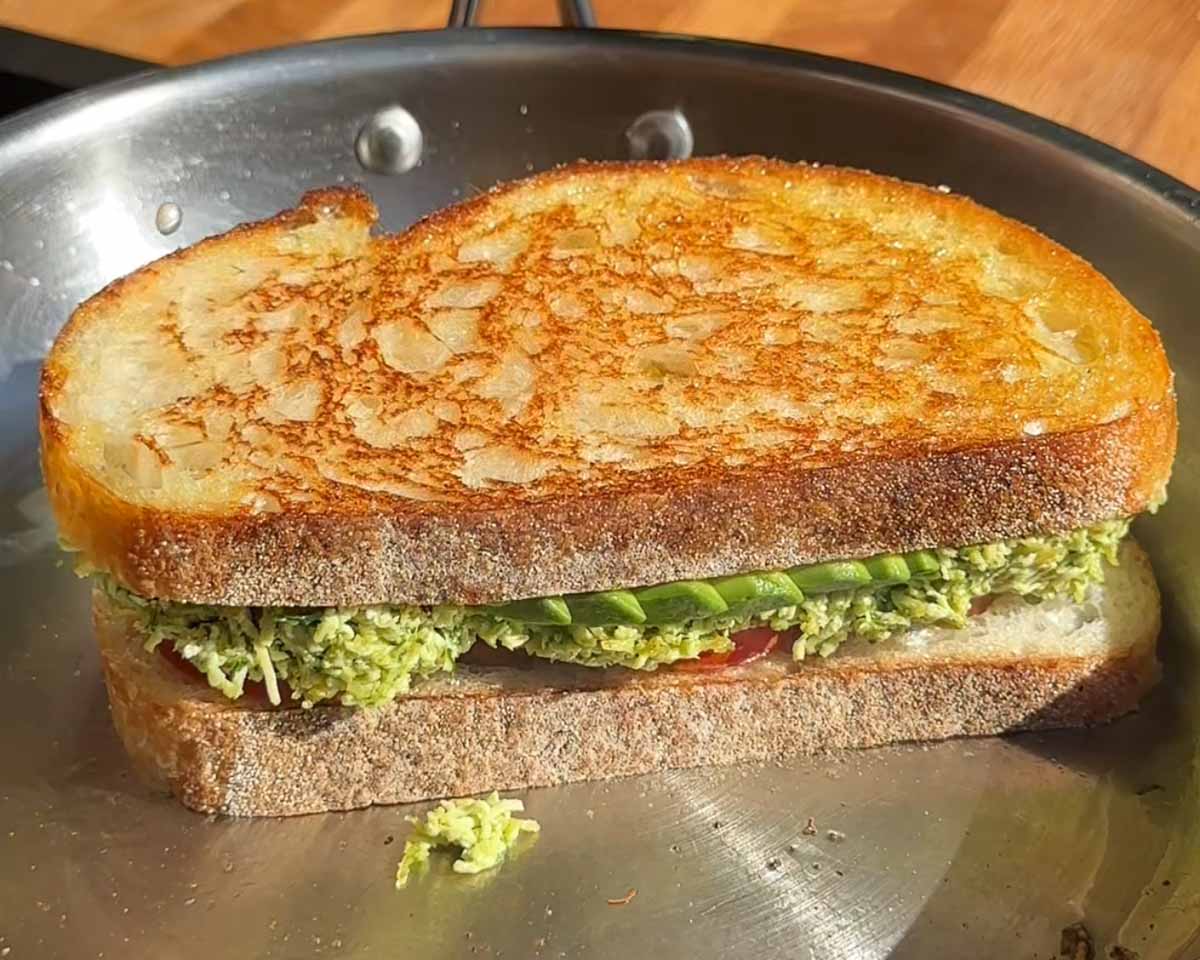 Tofucado pesto sandwich grilling in a pan until golden and crispy