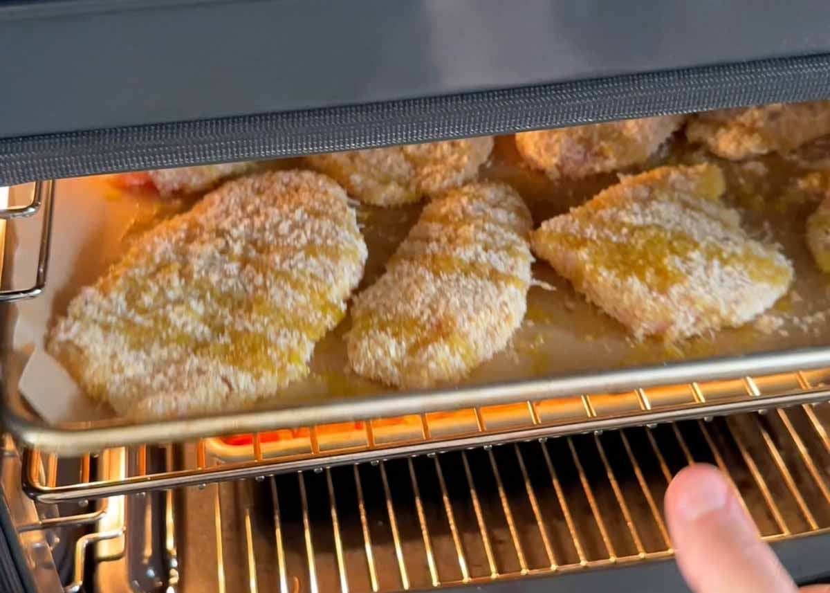 tray of hot honey parmesan crumbed chicken going in the oven