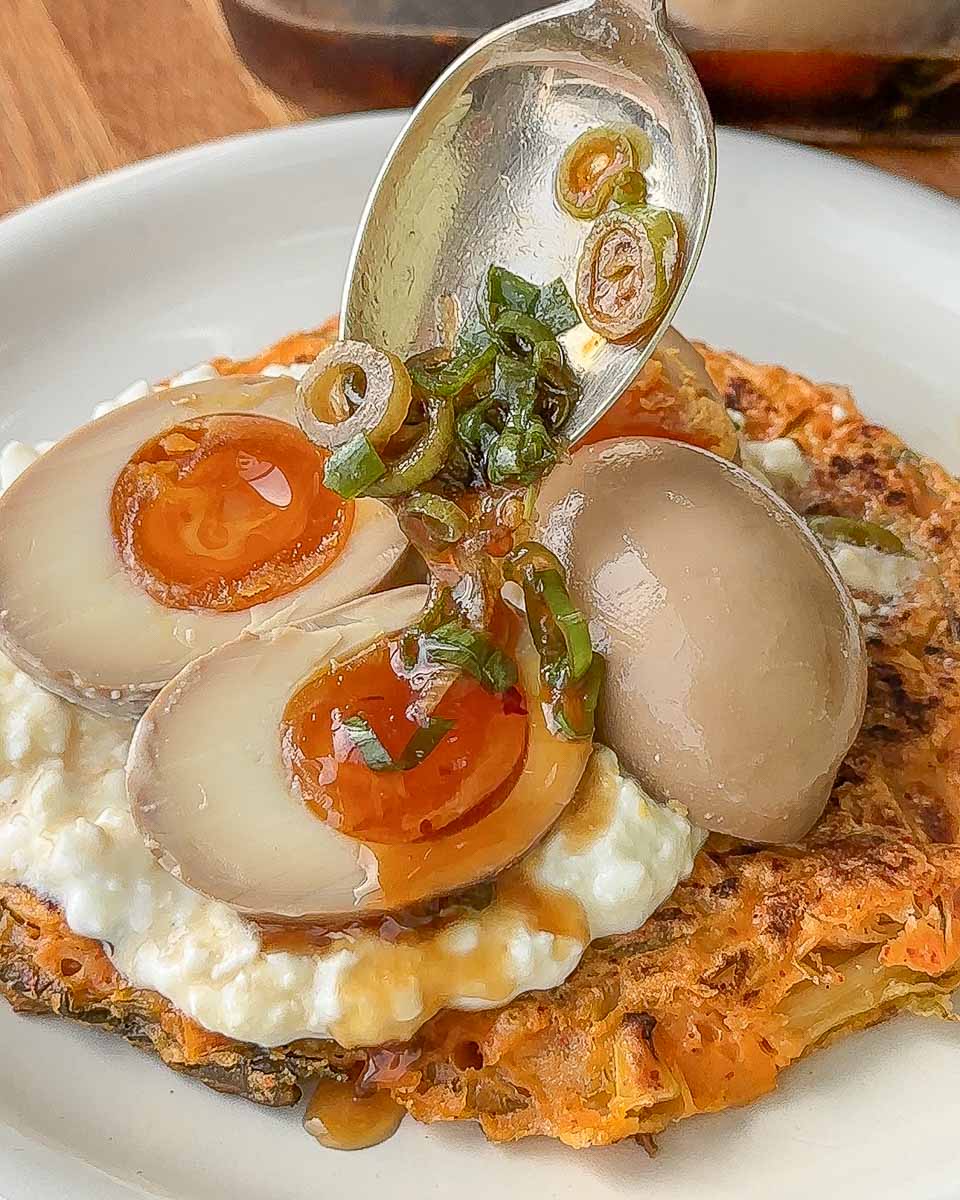 Pouring soy marinade over soft boiled eggs to make Korean marinated eggs