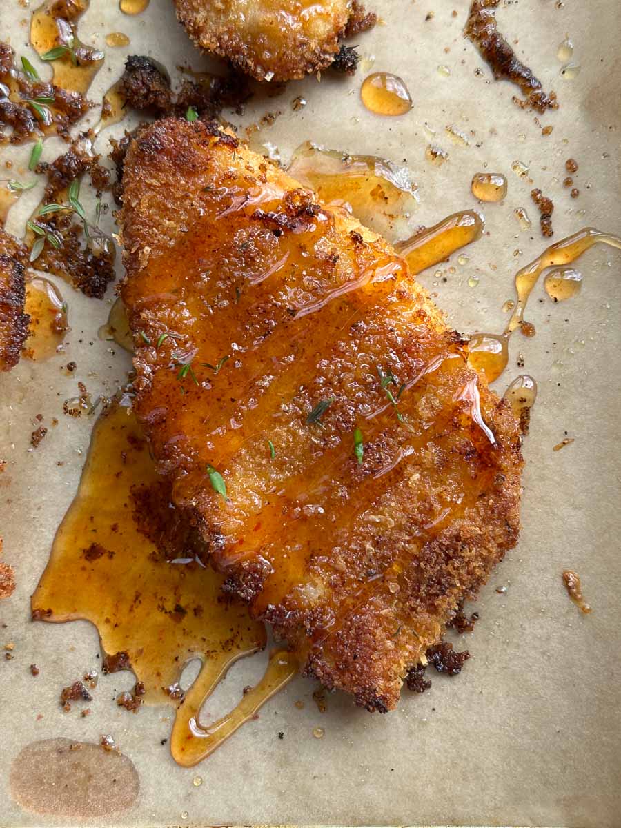 close up of hot honey parmesan crumbed chicken sitting on tray 