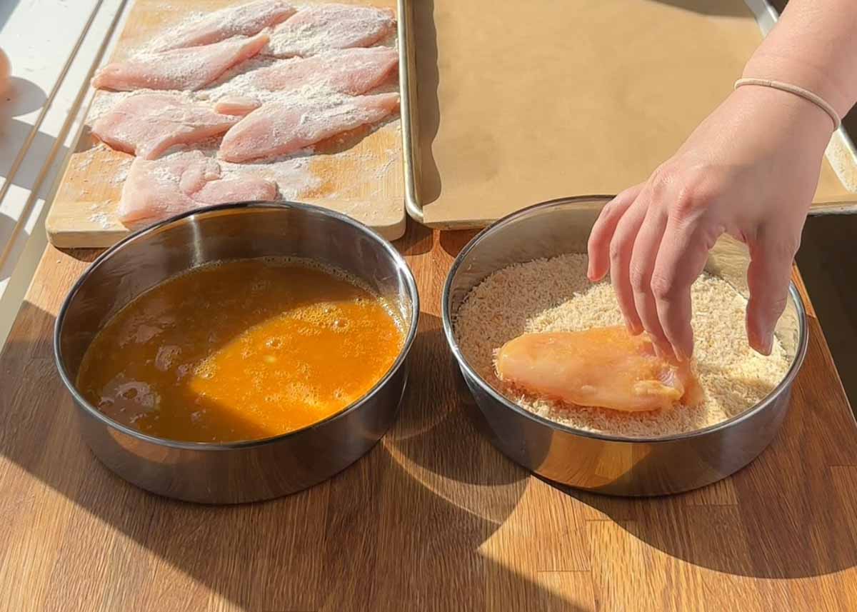 chicken breast being coated in panko crumbs