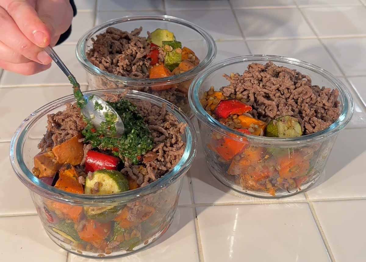 Assembling beef mince meal prep bowls with roasted vegetables and lentils