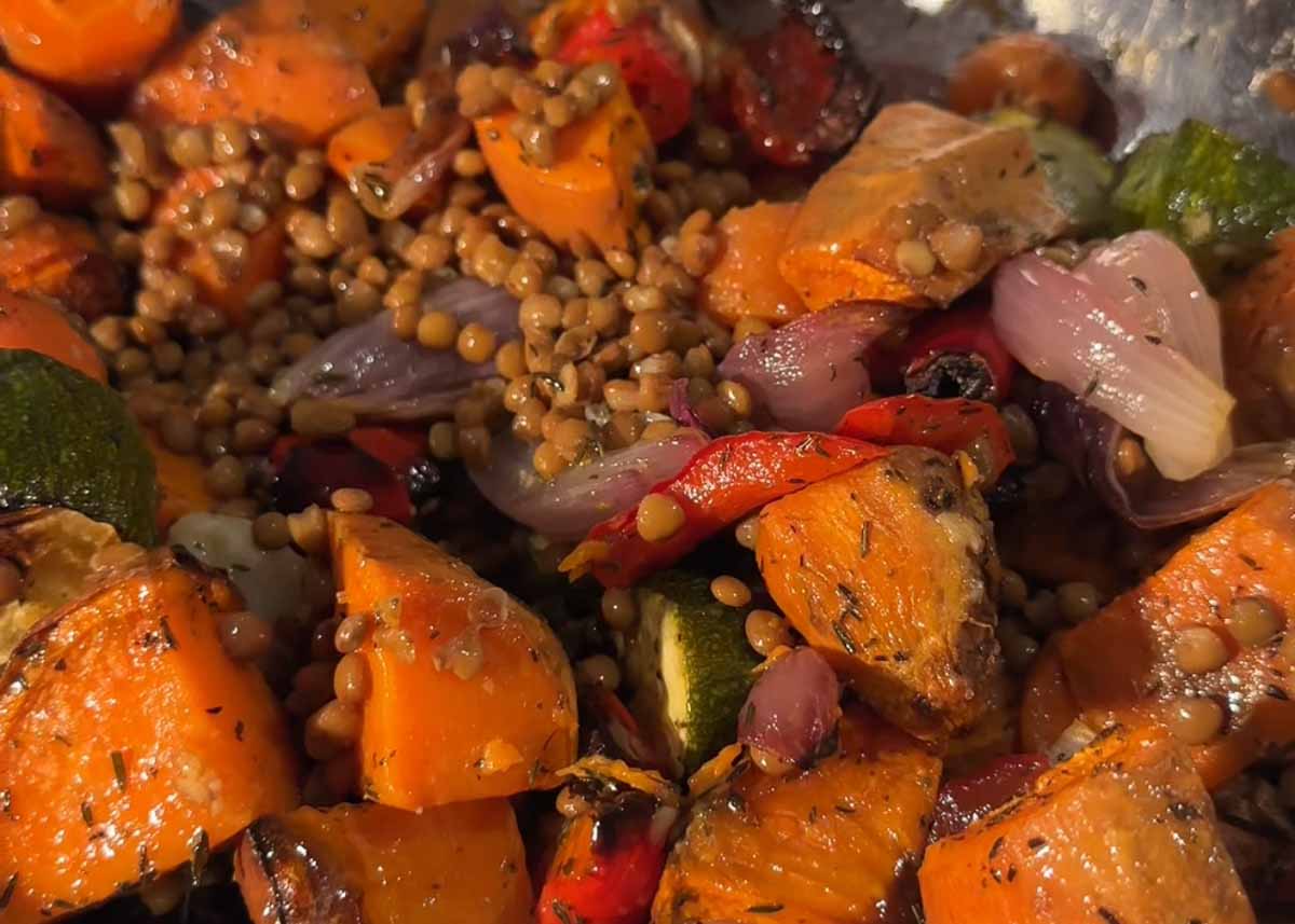 Caramelised roasted vegetables with golden edges fresh from the oven tossed with lentils