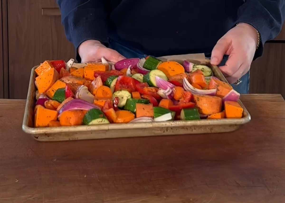 Seasoned vegetables spread on tray before roasting in oven