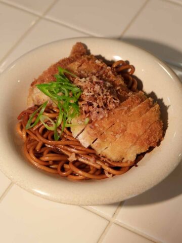 Sweet soy butter udon with crispy panko chicken sliced on top and garnished with spring onion