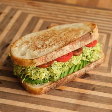 Tofucado pesto toasted sandwich with crispy golden bread, smashed avocado tofu filling and fresh tomato