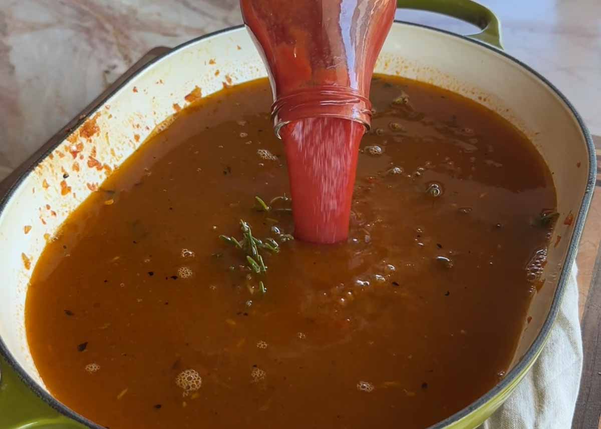 Passata being poured into rosé lamb shank ragu sauce