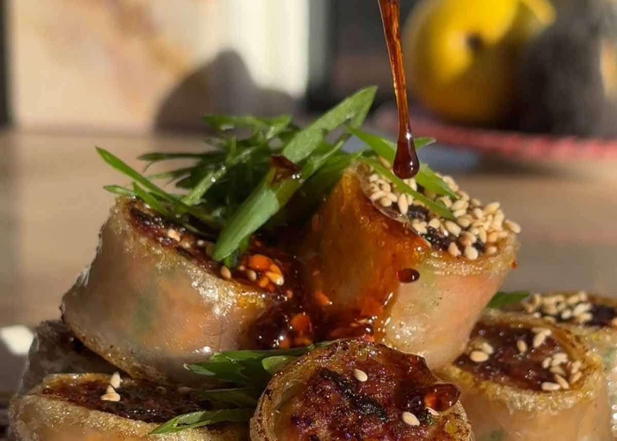Crispy rolled pork rice paper dumplings served with dipping sauce and herbs.