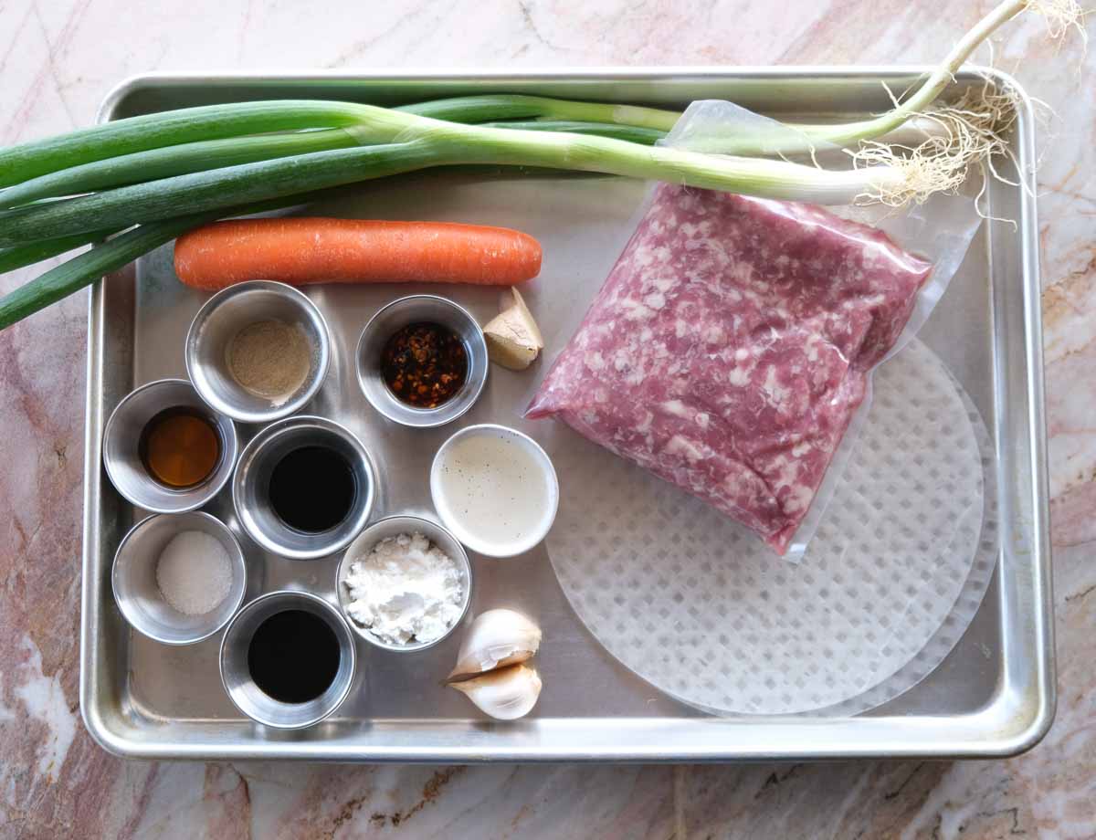 Ingredients for crispy rolled pork rice paper dumplings including pork mince, rice paper, carrot, spring onion, garlic and ginger.