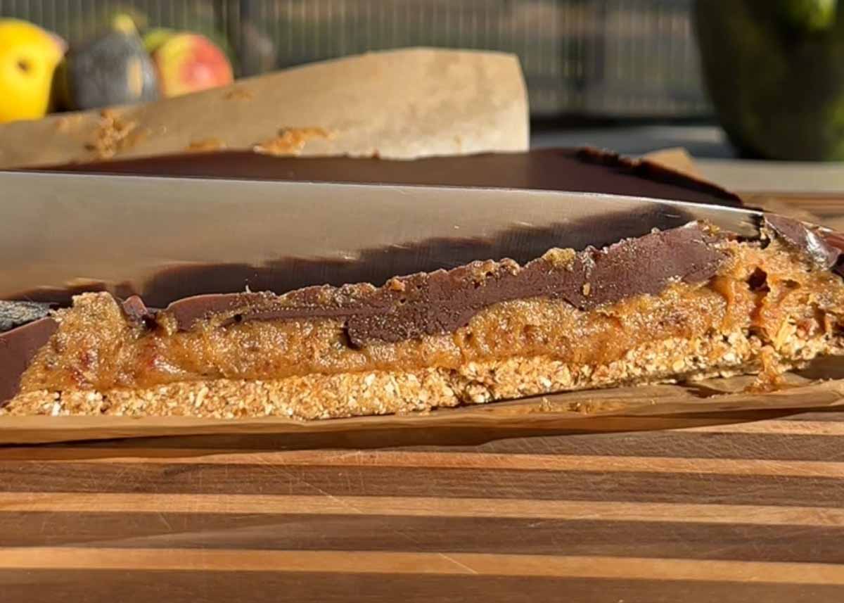 Cutting caramel slice into bars on a chopping board.