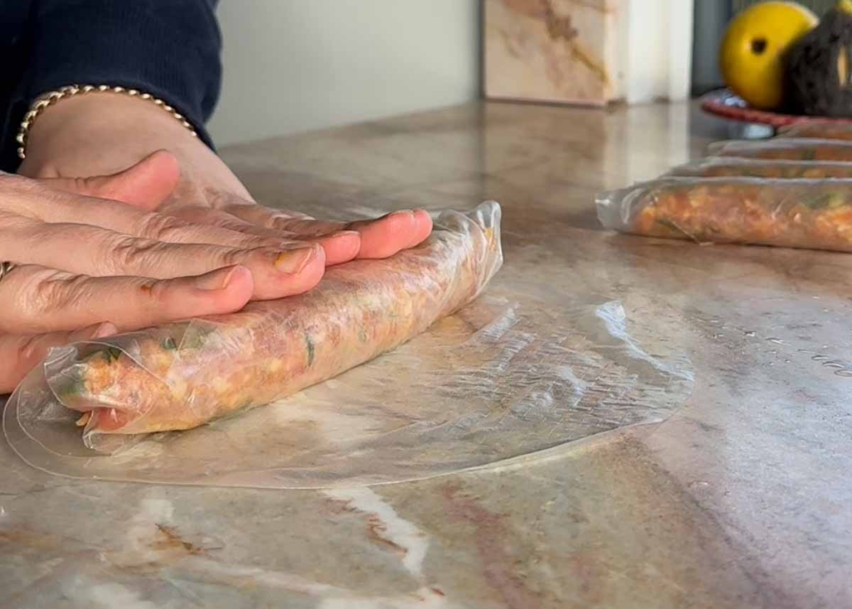Wrapping a pork rice paper log in a second layer of rice paper.