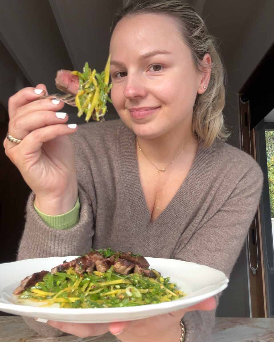 Sezzy holding plate of eye fillet with sliced snow pea salad