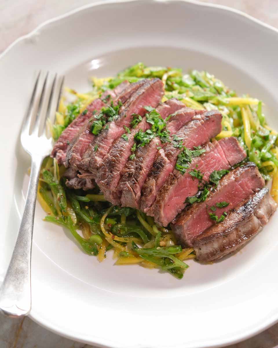 Sliced eye fillet steak served over fresh snow pea salad with herbs