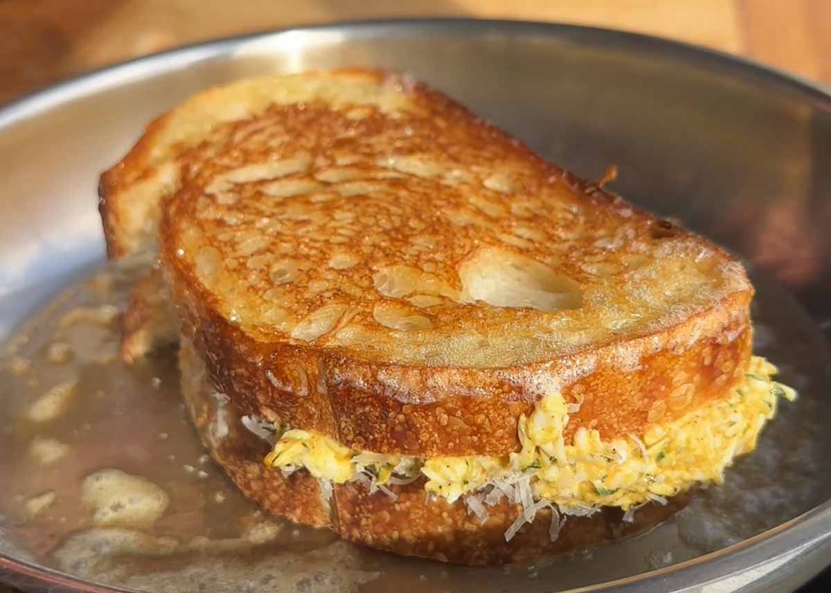 Curried grated egg toastie cooking in pan until golden and crispy