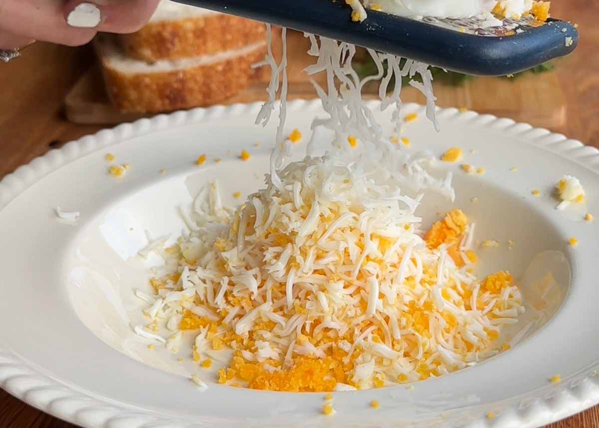 Grated boiled eggs in bowl for curried toastie filling