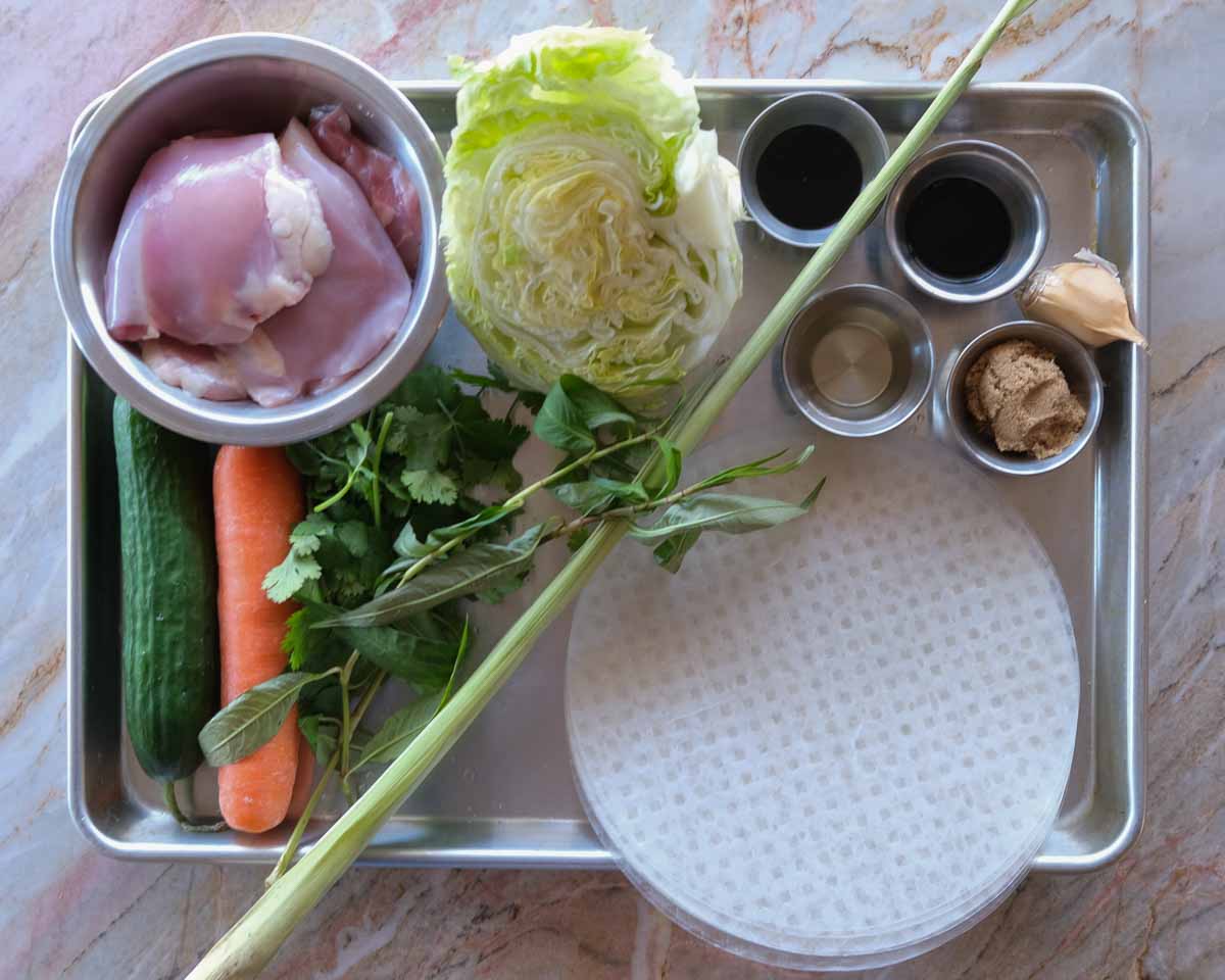 Ingredients for lemongrass chicken rice paper burritos including chicken thighs, herbs, vegetables and rice paper.
