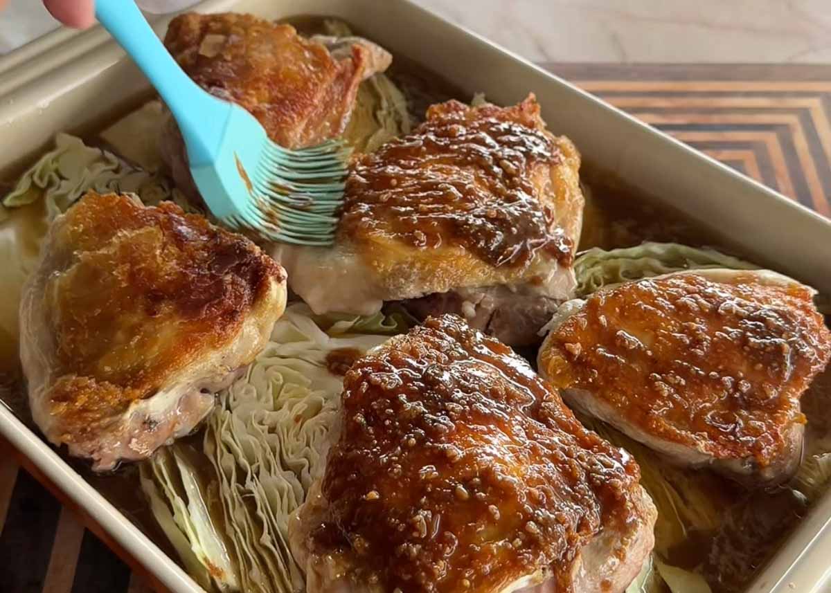 Miso honey glaze being brushed over browned chicken thighs before baking.