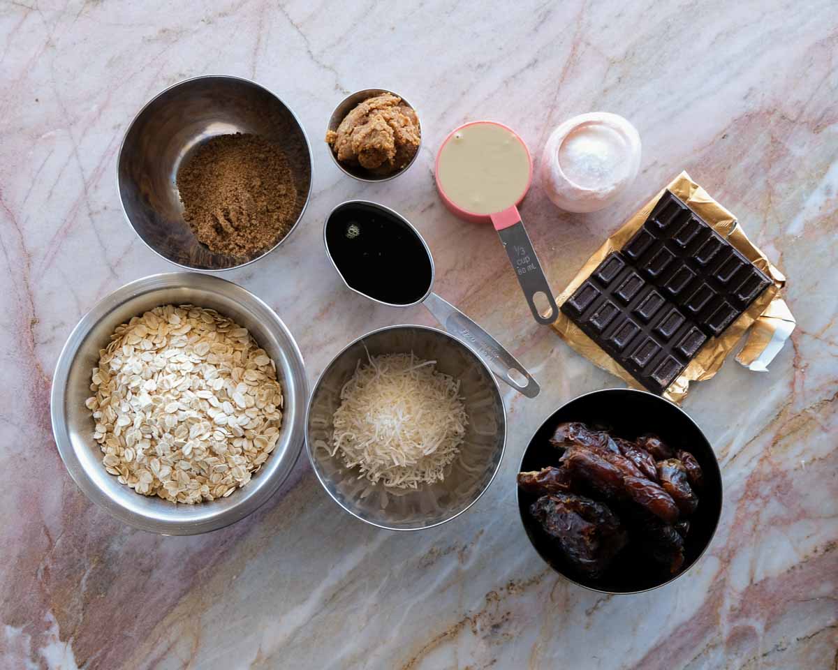 Ingredients for sugar free miso tahini caramel slice including oats, dates, tahini, miso and dark chocolate.