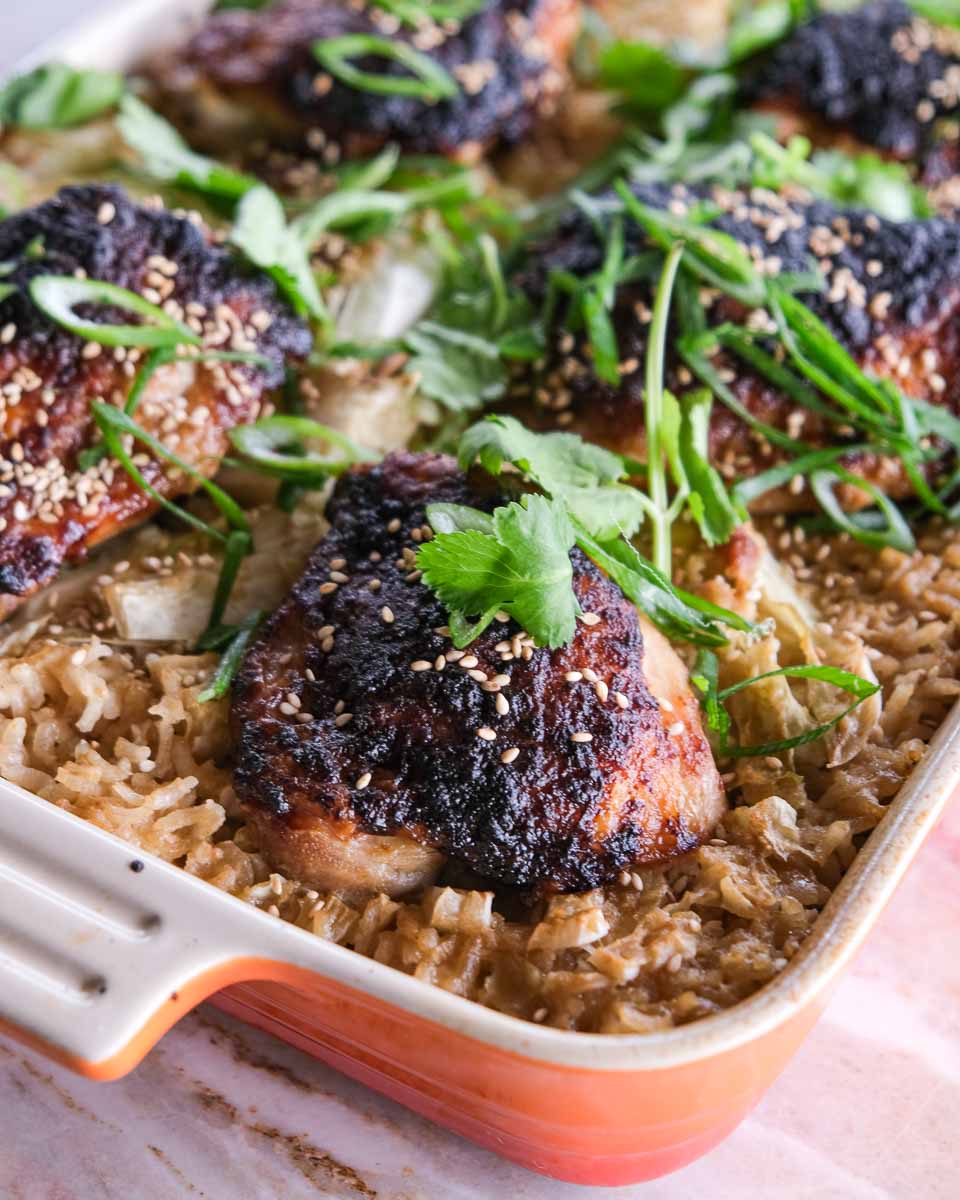 Close up of sticky miso glazed chicken thighs baked over cabbage and rice.