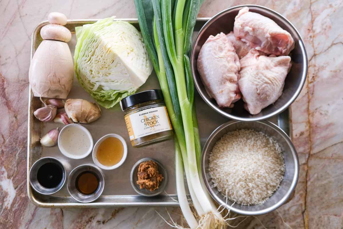 Ingredients for one tray miso chicken cabbage rice bake including chicken thighs, cabbage, spring onion, rice, garlic, ginger and miso.