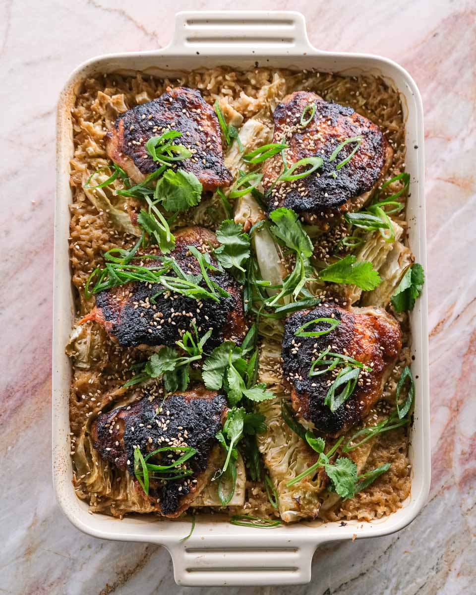 Overhead view of one tray miso chicken cabbage rice bake with sticky chicken thighs, cabbage wedges and sesame seeds.