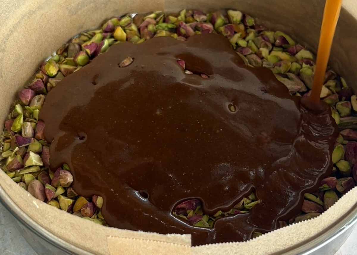 Pistachio caramel topping spread into a cake tin before baking.