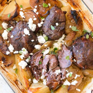 Slow cooked preserved lemon boneless lamb shanks with potatoes, feta and oregano in a rustic baking dish.