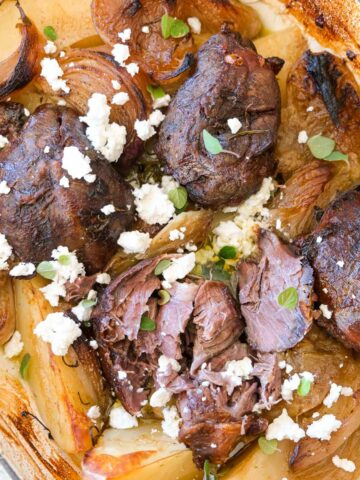 Slow cooked preserved lemon boneless lamb shanks with potatoes, feta and oregano in a rustic baking dish.