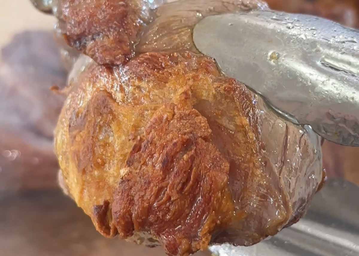 Boneless lamb shank meat being seared in a cast iron pot until browned
