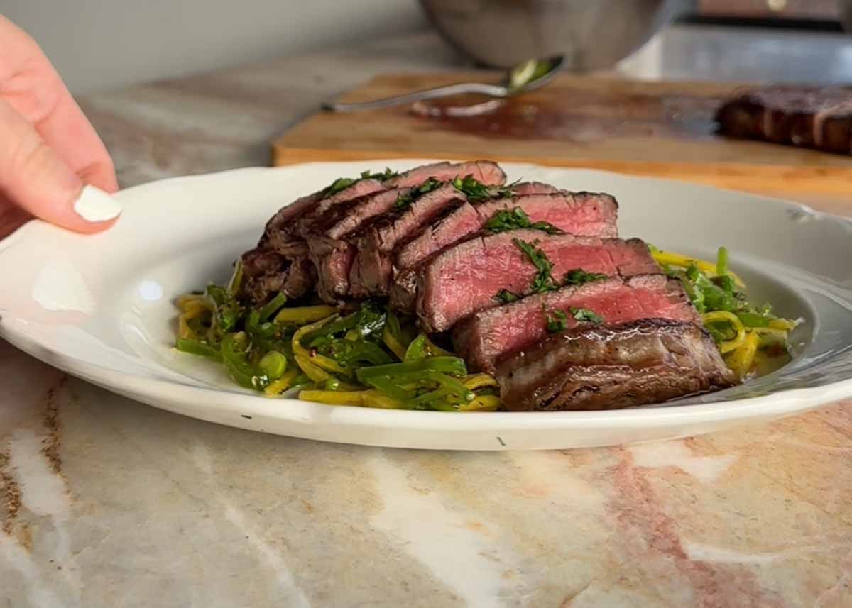 Sliced eye fillet being plated over fresh snow pea salad