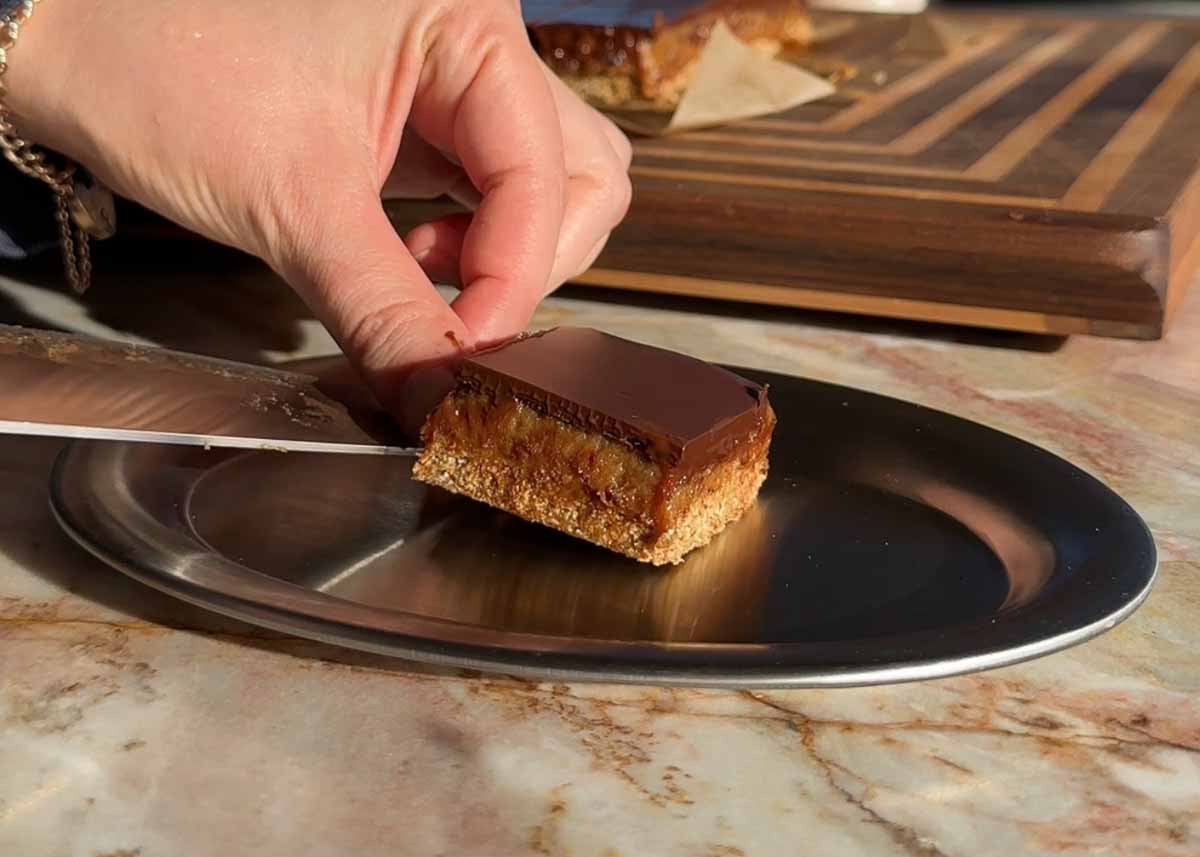 Serving a piece of sugar free caramel slice onto a plate.